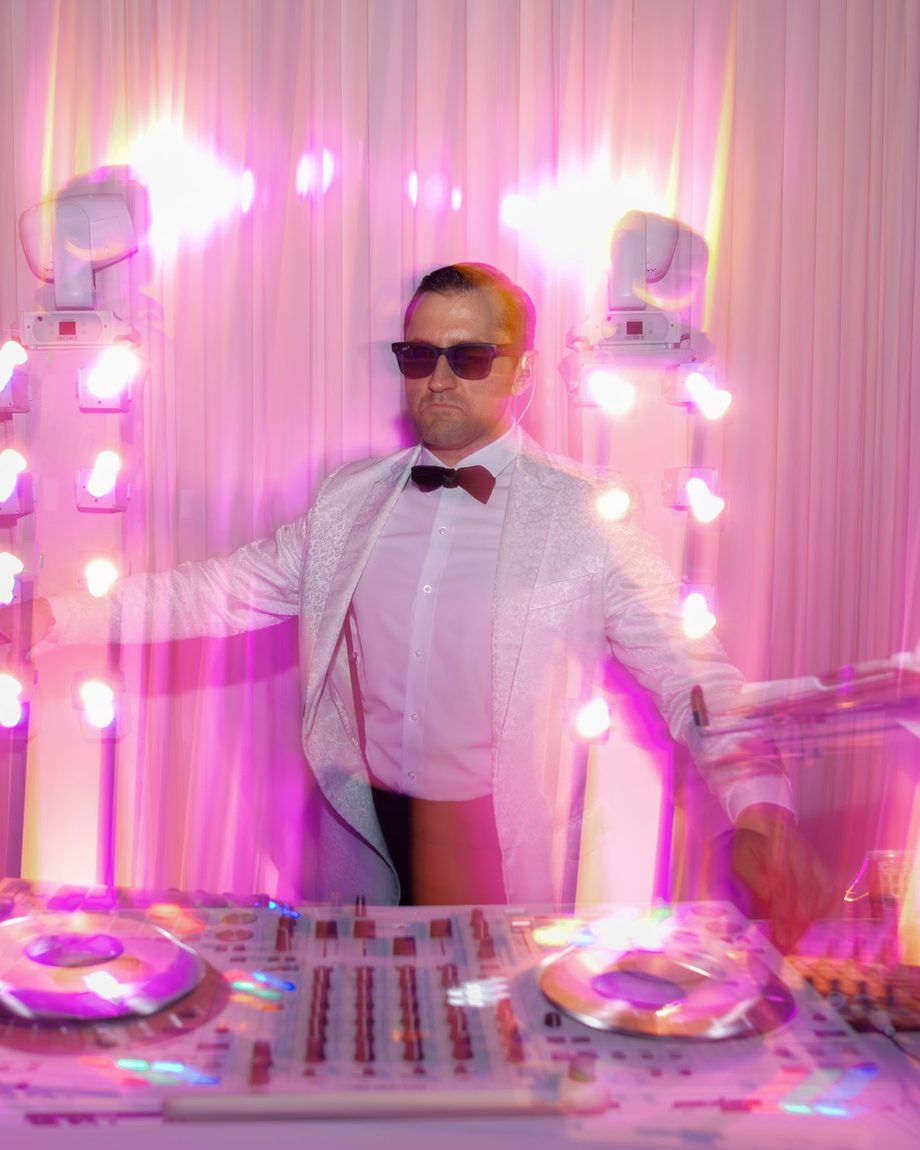 DJ Dayve under pink lights between two lighting towers